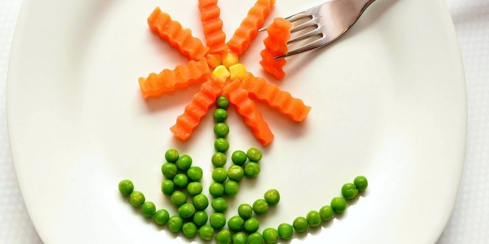 Prato com cenoura, ervilhas e grão de bico a formar uma flor