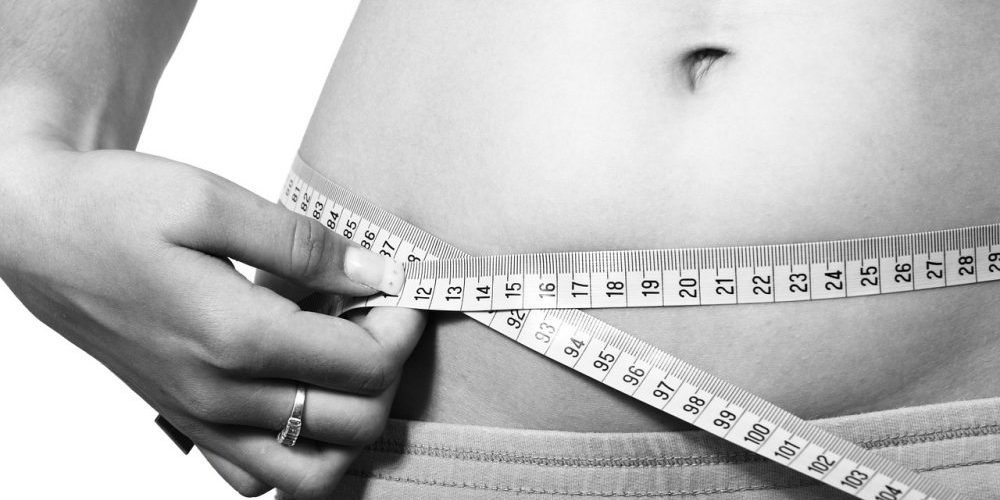 Fita métrica a medir o perímetro abdominal de uma mulher